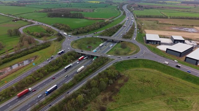 Aerial view of the busy A1M motorway cutting through the middle of Yorkshire showing travellers and commuters driving at rush hour with large roundabout at junction 47