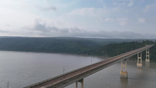Aerial perspective slowly panning over the deh cho bridge crossing the vast mackenzie river in the northwest territories, canada, showcasing the remote wilderness and impressive engineering