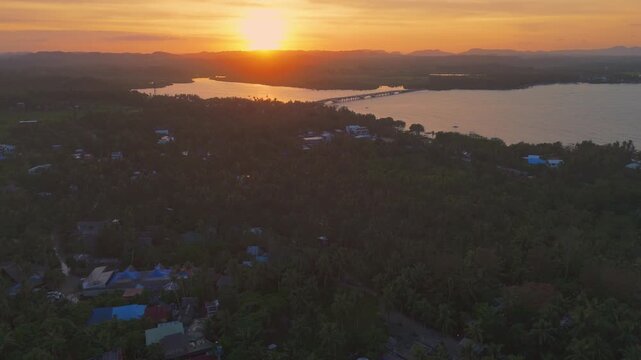 Stunning aerial panorama of the tropical forest and coastal lagoons of Siargao at sunset. Drone shot showing the sun reflecting on the water near General Luna in the Philippines
