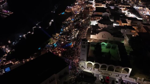 Top-down drone shot of tourists walking through the narrow alleys of Fira, gradually revealing the breathtaking island landscape of Santorini, white architecture, and caldera views.