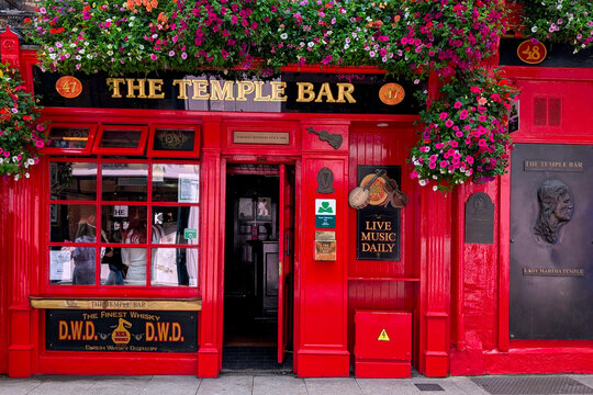 Dublin, Ireland - June 17, 2025: The Temple Bar. Iconic red color pub with flowers and live music signs in historic district of Dublin.