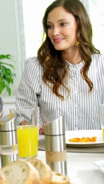 Smiling woman in striped shirt watching hand offering carrot at table with poultry and orange juice