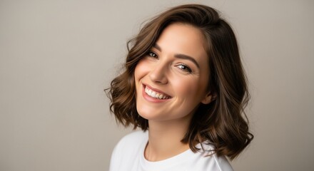 Fototapeta premium Beautiful young woman with a warm smile and wavy brown hair studio portrait