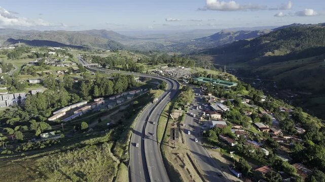 Drone flies backwards along a highway in the late afternoon before sunset in mountain town of Mbabane, Eswatini