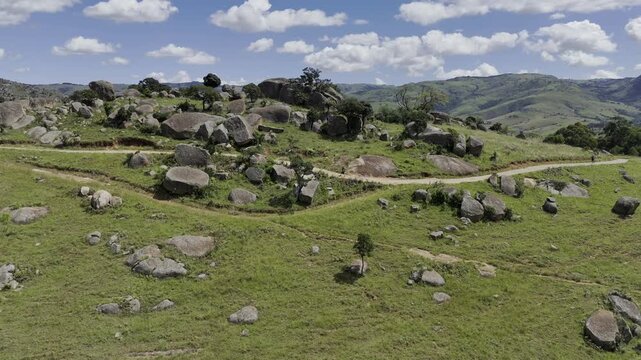Drone flies toward trail as two hikers work their way up Sibebe Rock on a sunny day near Mbabane, Eswatini