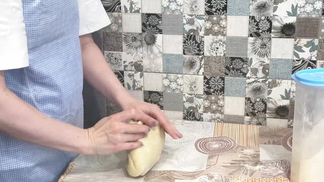An adult woman shaping and kneading bread dough by hand, kitchen cooking routine, homemade food preparation.