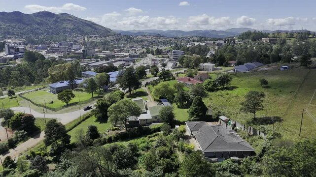 Drone does 360 around houses on a hill overlooking city in the early afternoon in mountain town of Mbabane, Eswatini