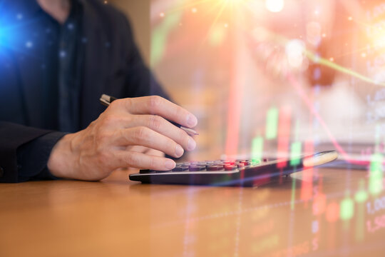 Close-up of a businessman using a calculator with financial data and stock market graph overlay, representing business analysis, investment planning, and financial growth.