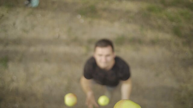 Juggler skillfully tossing vibrant green apples into the air, showcasing dynamic motion and concentration, with a blurred background enhancing the focus on the action sequence