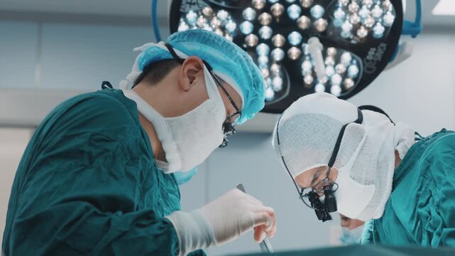 Multiple surgeons working together during a surgical procedure in an operating room. Hands in gloves carefully use medical instruments while coordinating actions in a sterile environment. Teamwork and