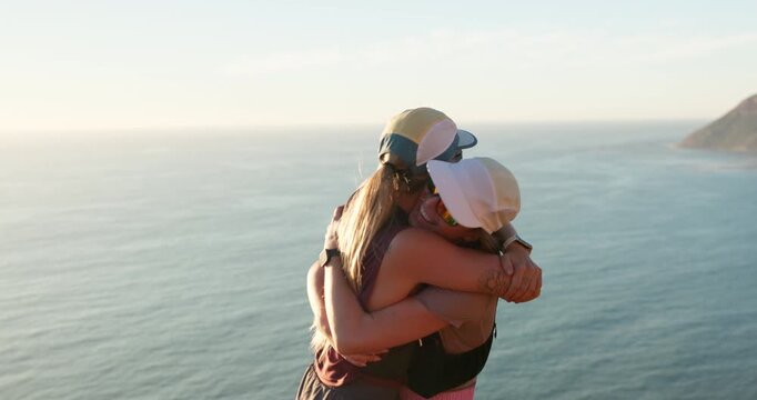 Friends, hiking and high five by sea with hug, sunglasses outdoor and fitness achievement together. Hiker, women and celebration by ocean with shades, bonding and embrace for workout accomplishment.