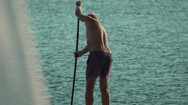 Paddleboarding, man, water, actively enjoying summer stand-up paddleboarding on a calm lake, engaging in recreational water sport