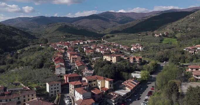 Aerial view of the historic village of Loro Ciuffenna with terracotta rooftops nestled among the rolling green hills and mountains of Tuscany, Loro Ciuffenna, Tuscany, Italy.