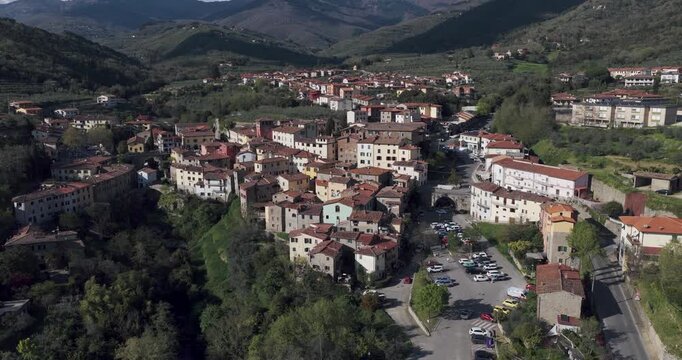 Aerial view of the historic stone buildings and red-tiled roofs of the village nestled in the green hills of Loro Ciuffenna, Tuscany, Italy.