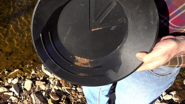 Gold dust and nuggets are left behind after washing soil in pan.