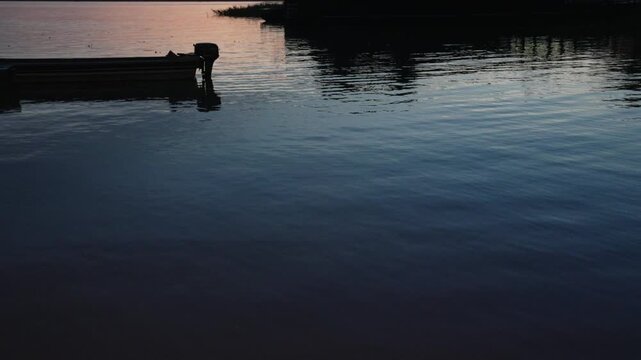 Slow motion tilt up showing a canoe and dock during a golden Amazon sunset