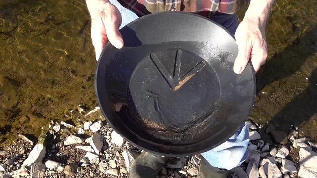 Gold collects in prospector's gold pan.