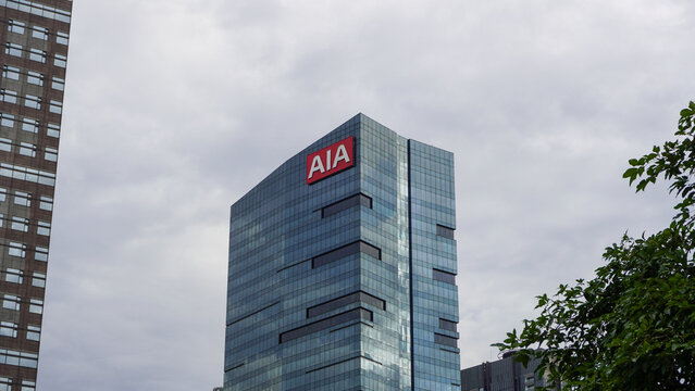 An editorial shot of the AIA Central building, a prominent glass-clad skyscraper located in the heart of Jakarta's financial district. The image highlights the sleek architectural design.