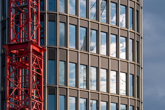 Modern berlin crane rises above urban construction as glass highrise facade and windows show strong reflections with contemporary architecture