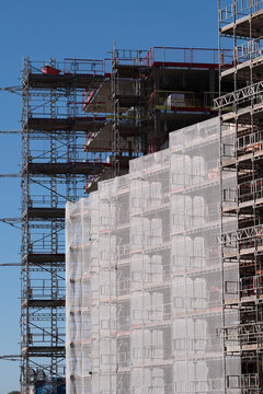 Oslo urban building rises in construction as scaffolding supports new facade sheeting and the structure feels industrial and modern within the city