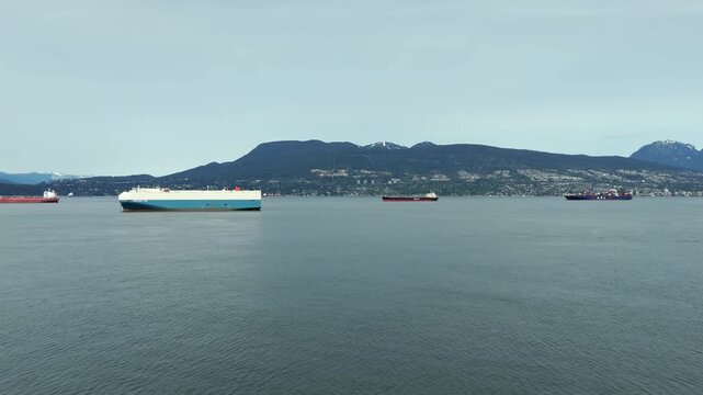 Ships Sail Across the Waters Near Jericho Beach, With the Stunning Mountains and Skyline in the Background, in Vancouver, British Columbia, Canada - Aerial Pullback Shot
