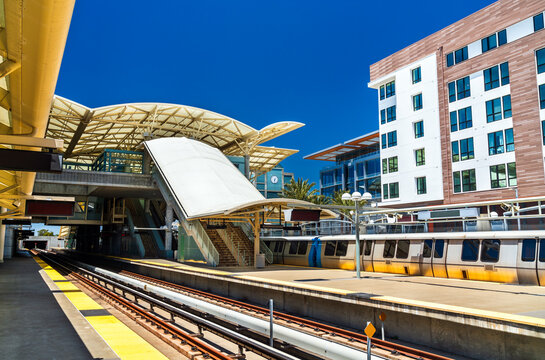 View of the platforms and modern architectural design of the Millbrae Transit Station with a bart train and urban housing near San Francisco in California, United States