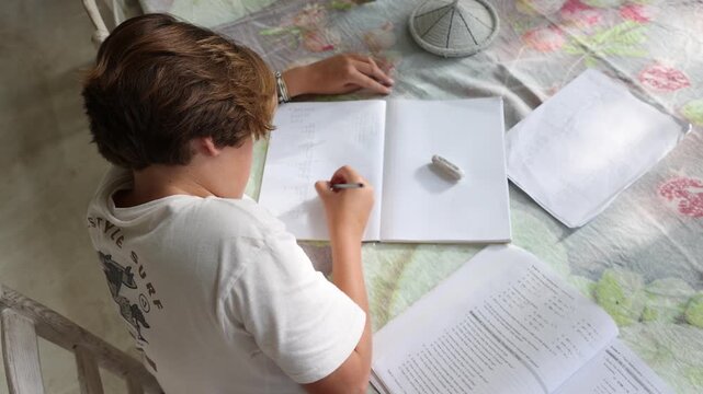 young boy doing homework on table at home