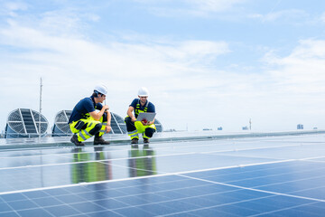 Engineers working on solar panels with laptop on rooftop, renewable energy system installation and...