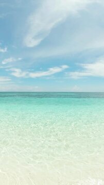 Crystal clear sea water and waves crashing over sandy beach in Mantigue Island. Camiguin, Philippines. Vertical view.