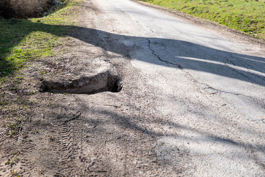 Roadside Erosion Creating Dangerous Hole and Damaged Edge of Rural Asphalt Road
