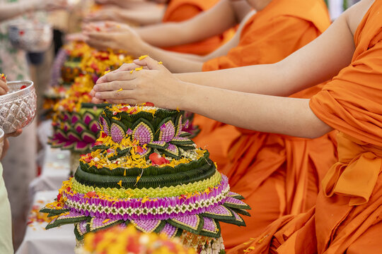Asian monk pouring water blessing flower arrangement festival orange robe religion tradition calm peaceful ceremony spiritual belief cultural offering celebration custom ritual