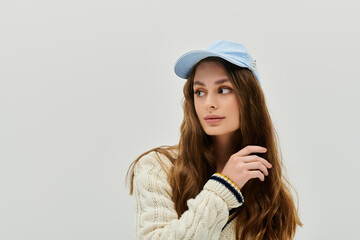 Naklejka premium Beautiful young woman gazes thoughtfully while wearing a cap and cozy sweater indoors