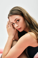 Fototapeta premium Captivating young woman with flowing hair gazes thoughtfully against a soft backdrop