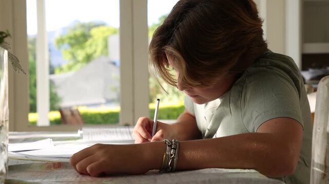 young boy doing homework on table at home
