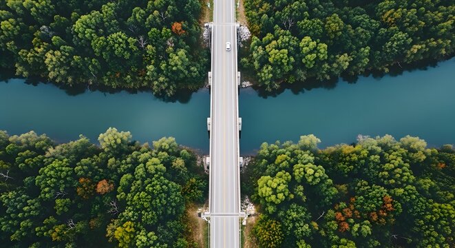 Aerial view of a concrete bridge spanning a turquoise river, surrounded by dense, vibrant green forest, showcasing a scenic landscape with a single vehicle traveling across.