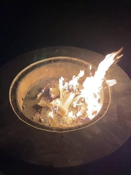 Backyard fire pit burns paper with bright flames at night
