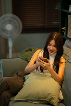 Young woman browsing on smartphone while sitting comfortably on sofa at home