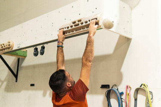 Male athlete training finger strength on hangboard