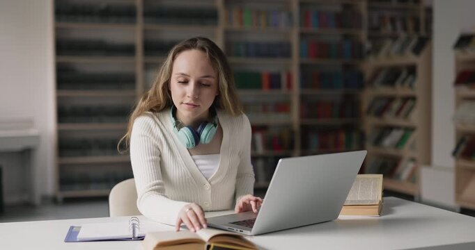 Female student studying, preparing for university admission or college exams, e-learning using laptop, researching information sitting at desk in library. Digital education, online learning, knowledge