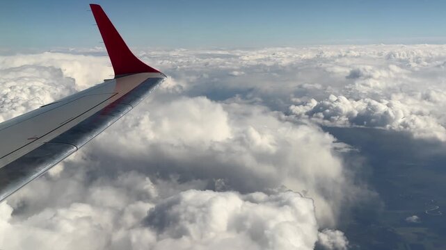 View from Iasi to Wien airplane window showing the wing above a sea of clouds with glimpses of the landscape below