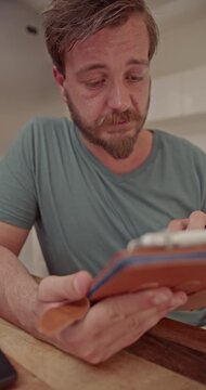 Observing two men focused on their respective tasks, one writing in a notebook, the other interacting with a digital tablet in a comfortable home environment.
