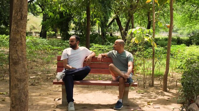 Two men sitting on a red bench in Lodhi Garden, New Delhi, India
