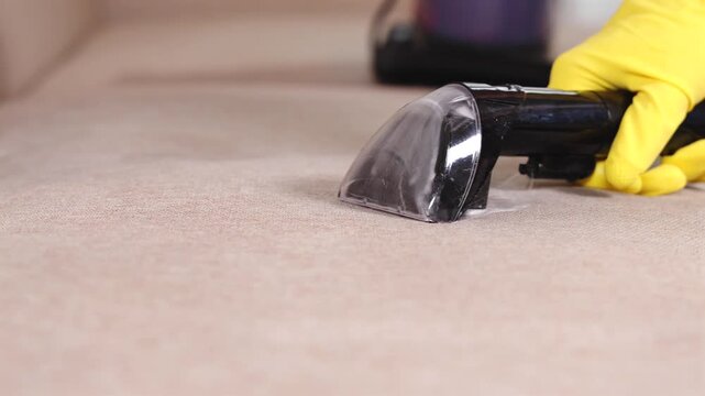 Gros plan sur une shampouineuse qui fait de la mousse sur un canap&eacute;. La machine sert pour le nettoyage de tissus d'ameublement.