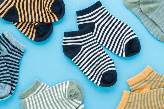 New colorful striped short socks for little child boy on light blue table background. Pastel color. Closeup. Clothes pattern. Top down view.