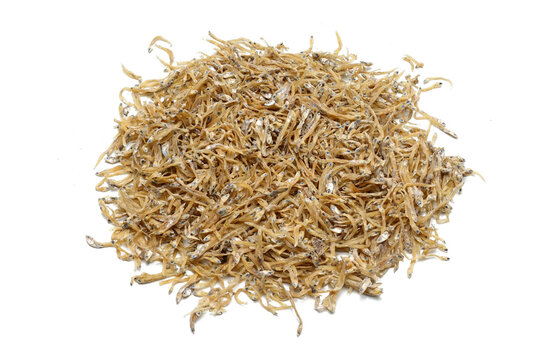 A pile of dried anchovies (ikan teri medan) isolated white background. the textured details of the naturally dried small fish. culinary content, traditional cooking ingredients, seafood markets