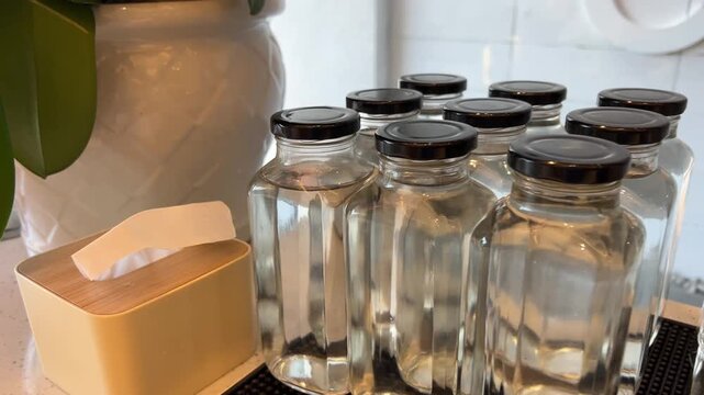 Self service water station with glass jars and upside down empty glasses on a buffet table showing clean minimal hospitality setup in a modern dining area.