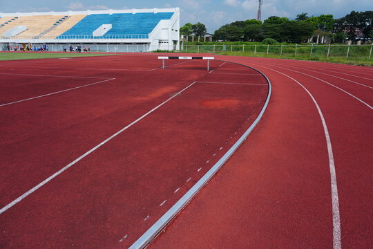 Red athletic running track with steeplechase hurdle in stadium