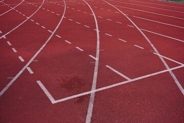 Fototapeta premium Red running track with white lane markings and dashed lines