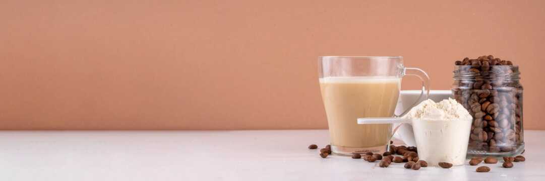 Protein coffee, whey isolate latte drink with whey protein powder in scoop and coffee beans, on kitchen table copy space