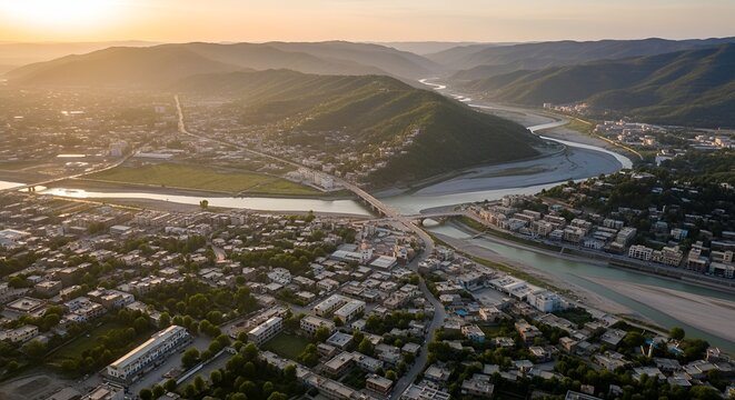 Aerial view of a city nestled in a valley with a river and mountains at sunset